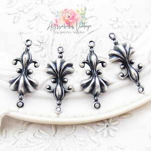 May include: Four silver-toned metal charms with a fleur-de-lis design. Each charm has two jump rings for attaching to jewelry.