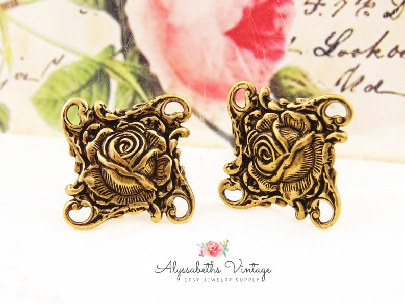 May include: Two gold-tone metal rose charms with four holes for attaching to jewelry or other crafts. The roses are detailed and have a vintage look.