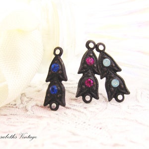 Puede incluir: Dos abalorios de metal de estilo antiguo en forma de flor con tres piedras de cristal cada uno. Los abalorios tienen forma de flor con tres p&eacute;talos. Las piedras de cristal son azules, rosas y azul claro.