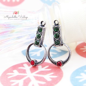 May include: Silver-toned earrings with a traffic light design. Each earring features three green and one red gemstone. The earrings have a circular loop and a rectangular top with a small loop for hanging. The text "Alyssabeths Vintage" is visible.