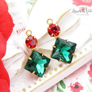 May include: Two gold-tone earring charms with red and green faceted glass stones. The charms are in the shape of a square and a circle. The text "Ayssabelths Vintage ETSY Jewelry Supply" is visible in the background.