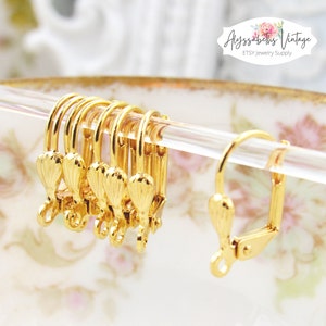 May include: Gold-toned earring findings with a decorative scallop design. The findings are shown on a clear display rod.  The findings are for jewelry making.