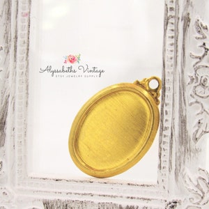 May include: Gold oval-shaped pendant with a textured surface and a loop at the top for attaching a chain. The pendant is in a white frame.