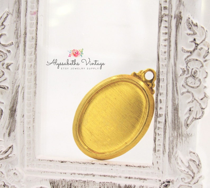 May include: Gold oval-shaped pendant with a textured surface and a loop at the top for attaching a chain. The pendant is in a white frame.