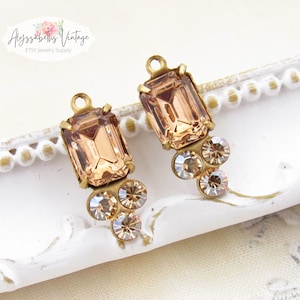 May include: Two gold-tone metal earring charms with a peach-colored emerald-cut rhinestone and smaller clear rhinestones.