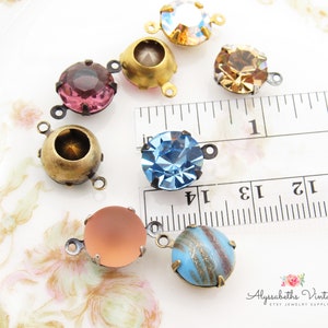 May include: Assortment of colorful glass cabochons with antique brass settings. The cabochons are approximately 1 inch in diameter and have a variety of colors, including pink, blue, and brown. The settings have a loop on each side for attaching to jewelry.