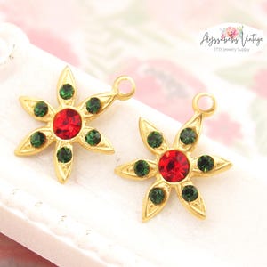 May include: Two gold-tone flower charms with red and green rhinestones. Each charm has a loop at the top for attaching to jewelry.