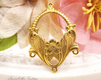 May include: Gold-toned metal pendant with a floral design. The pendant has a large oval opening in the center and three loops on the bottom.