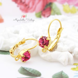 May include: Gold hoop earrings with a pink rhinestone in the centre. The earrings have a lever back closure.