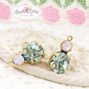 May include: Two antique gold-tone metal charms with light blue and pink crystal rhinestones. The charms are perfect for jewelry making.