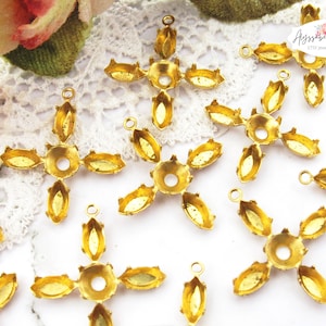 May include: Ten gold-tone metal settings for cabochon stones. Each setting has a four-pronged design with a round center hole. The settings are ideal for jewelry making.