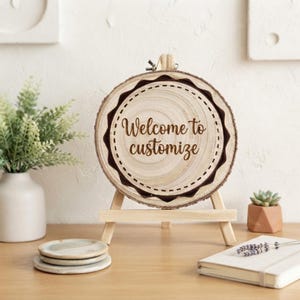 May include: A circular wood slice sign featuring the laser-engraved text "Welcome to customize" in a dark brown script font. The sign is displayed on a small wooden easel and features a decorative dark brown scalloped border design.