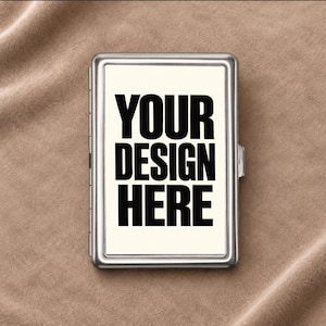 Könnte beinhalten: Ein rechteckiges Zigarettenetui aus silberfarbenem Metall mit einem weißen Mittelfeld, auf dem der fettgedruckte schwarze Text YOUR DESIGN HERE steht. Das Etui verfügt über einen Metallrahmen und einen seitlichen Verschlussmechanismus.