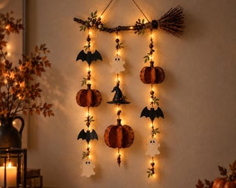 Puede incluir: Una decoración de pared que presenta una rama de madera horizontal con un extremo en forma de escoba, suspendida por un cordel. Tres hileras verticales de luces LED cálidas están adornadas con figuras de madera de murciélagos, fantasmas, calabazas y un sombrero de bruja.