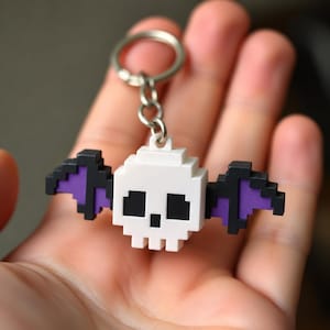Llavero con calavera de murciélago pixelada, llavero retro de videojuegos pintado a mano, accesorio espeluznante individual impreso en 3D