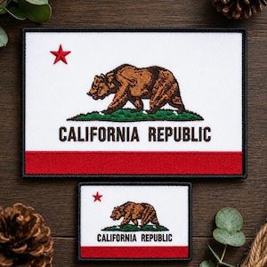 May include: Two rectangular embroidered patches featuring the California Republic flag design. Each patch displays a white background, a red star in the upper left, a brown grizzly bear walking on green grass, and the text CALIFORNIA REPUBLIC.