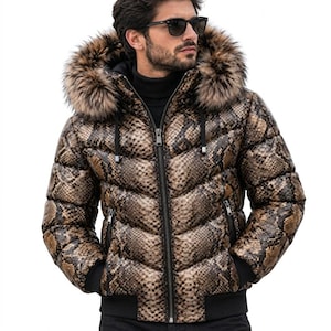 May include: A puffer jacket featuring a brown and black snakeskin pattern, a hood with a thick brown faux fur trim, a black front zipper, black ribbed cuffs, and black drawstrings. The jacket has a quilted design and a high collar.