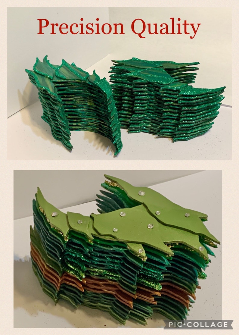 May include: A stack of green, gold, and copper glitter paper scales. The scales are layered and have a slightly curved shape. The scales are arranged in a pattern that resembles a dragon's tail.