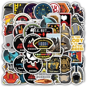 May include: A collection of assorted vinyl stickers featuring various graphic designs, including military-style emblems, character helmets, and text such as Malevelon Creek Veteran, Just Dive, and My Other Ride Is A Hellpod, in a mix of colors.