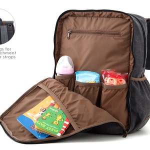 May include: A gray canvas diaper bag backpack with multiple pockets and a brown interior. The backpack is open and shows a baby bottle, wipes, and snacks inside. The backpack has two rings on the top for attaching to a stroller.