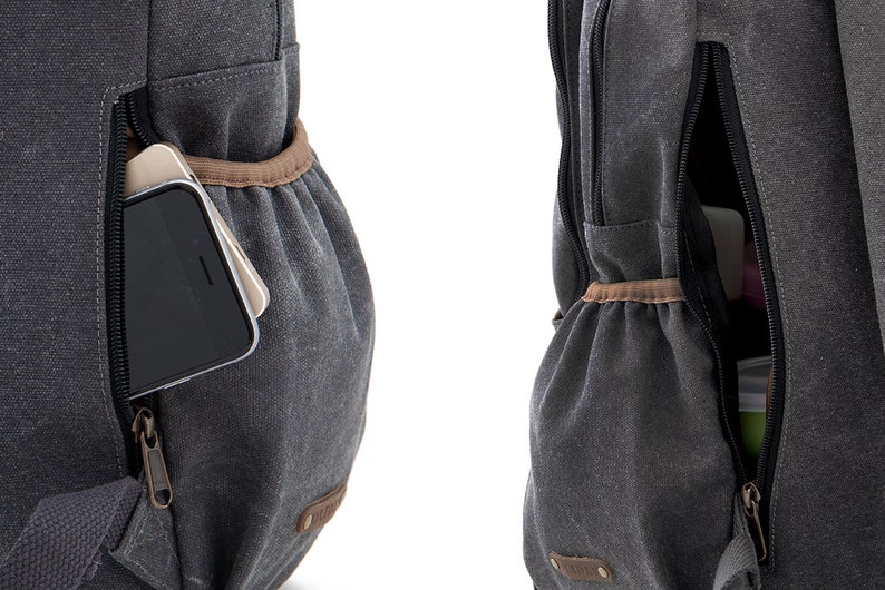May include: A gray canvas backpack with a zippered pocket on the front. The pocket has a brown leather trim and a zipper pull. A cell phone is visible inside the pocket.
