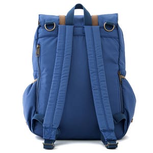 May include: A blue backpack with brown leather accents and adjustable straps. The backpack has a zippered pocket on the side and a flap closure with a buckle.