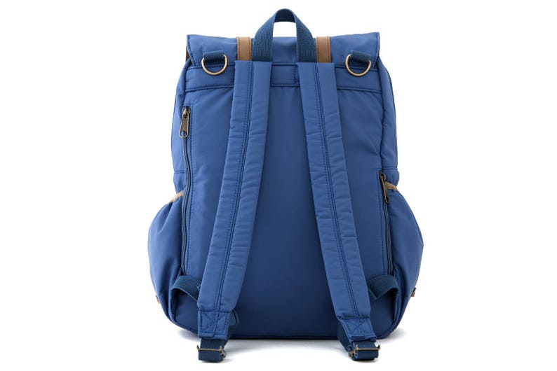 May include: A blue backpack with brown leather accents and adjustable straps. The backpack has a zippered pocket on the side and a flap closure with a buckle.