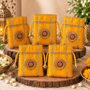 May include: Five bright yellow drawstring pouches featuring vertical gold metallic trim and a central circular medallion with a red and gold floral design. Each pouch is finished with small gold bell charms attached to the ends of the drawstrings.
