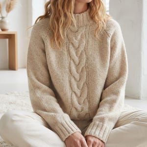 May include: A beige cable-knit sweater with a mock neck collar and long sleeves. The garment features a prominent vertical braided cable pattern running down the center of the chest, crafted from a textured, speckled yarn with ribbed cuffs.