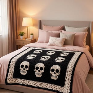 May include: A rectangular crochet blanket featuring a black background with nine white skull motifs arranged in a grid. The blanket is finished with a wide, intricate white crocheted border that frames the central black panel and skulls.