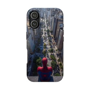 May include: A smartphone case featuring a high-angle view of a city street with tall buildings and trees. In the foreground, a red and blue costumed figure with a spider emblem on the back sits on a ledge, overlooking the urban landscape below.