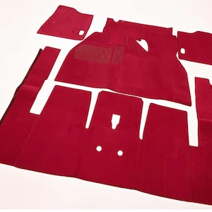 Peut inclure: Un ensemble de tapis de sol automobiles rouge profond avec une texture en moquette épaisse. La collection comprend plusieurs pièces distinctes avec des découpes précises pour les commandes, dont une section à motif losange.