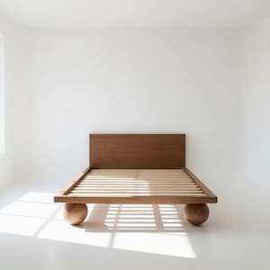 May include: A low-profile wooden bed frame featuring a rectangular headboard with a natural wood grain finish. The platform base is supported by four large, spherical wooden feet and includes a series of horizontal slats for mattress support.