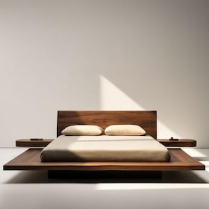 May include: A low-profile platform bed frame crafted from dark brown wood with a wide, flat base and an integrated headboard. The bed features two attached side tables and is dressed with a light beige mattress and two matching rectangular pillows.