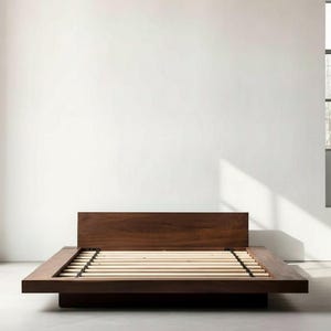 May include: A low-profile platform bed frame constructed from dark brown wood, featuring a rectangular headboard and a wide wooden border surrounding a series of light-coloured, horizontal wooden slats designed to support a mattress.