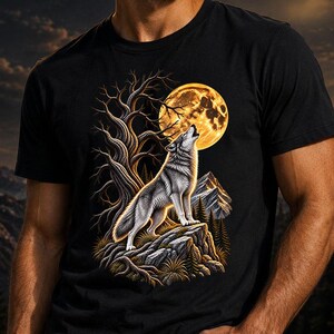 Könnte beinhalten: Ein schwarzes T-Shirt mit kurzen Ärmeln und einem Grafikdruck eines grauen Wolfes, der einen großen, leuchtend gelben Vollmond anheult. Die Szene zeigt einen knorrigen, blattlosen Baum, felsiges Gelände und ferne Berggipfel in Gold- und Brauntönen.
