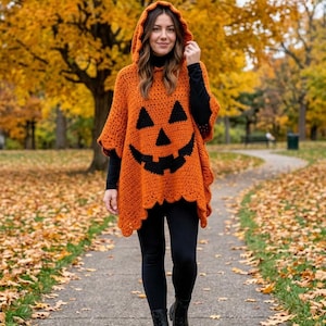 May include: A bright orange crochet hooded poncho featuring a large black jack-o'-lantern face design on the front. The garment has a scalloped hemline and is worn over a black long-sleeved shirt, black leggings, and black lace-up boots.