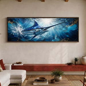 May include: A panoramic wall art piece featuring a blue marlin swimming through deep blue ocean water. The fish is depicted with a long bill and dorsal fin, surrounded by white sea foam and light rays filtering down from the surface of the water.