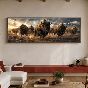 May include: A panoramic wall art print featuring a herd of brown bison running across a dusty, dry landscape under a dramatic, cloudy sky with golden sunlight. The scene captures the powerful movement of the animals with mountains in the distance.