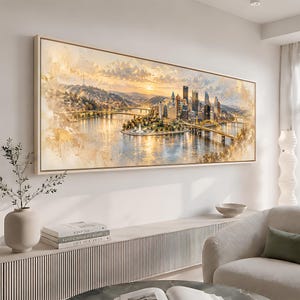 Op de afbeelding: Een rechthoekige wandkunstprint met een panoramisch stadsgezicht van Pittsburgh bij zonsondergang in aquarel-stijl. De scène toont de samenvloeiing van drie rivieren, bruggen en de skyline van het centrum in warme goudtinten.