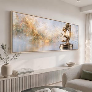 May include: A rectangular wall art piece featuring a gold-toned microscope on the right side, set against an abstract background of swirling gold, white, and soft blue hues with faint, delicate chemical structure diagrams overlaid throughout.