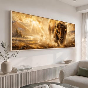 May include: A rectangular wall art print featuring a golden-toned landscape with a large bison charging forward. The scene is illuminated by bright sunbeams breaking through clouds over a grassy field with mountains in the background.