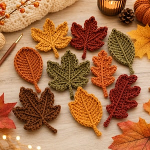 Puede incluir: Una colección de nueve hojas de otoño tejidas a ganchillo en varias formas y colores, incluyendo tonos amarillos, naranjas, rojos, marrones y verdes. Las hojas presentan texturas de hilo detalladas sobre una superficie de madera clara.