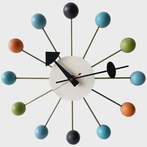 May include: A starburst wall clock featuring a central white circular face with black hands and a thin red second hand. Twelve thin metal spokes extend outward, each tipped with a wooden sphere in shades of blue, green, orange, and black.