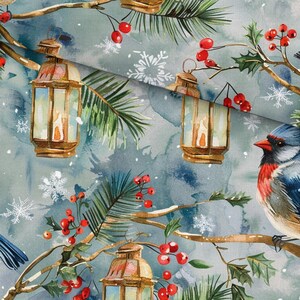 May include: Fabric featuring a watercolor print of brown lanterns, pine branches, red holly berries, and white snowflakes on a muted blue-gray background. A bird with a red chest and blue head is perched on a branch among the winter elements.