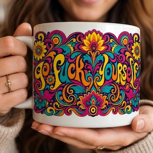 May include: A white ceramic mug featuring a vibrant, multi-colored psychedelic floral pattern with intricate swirls and paisley-like designs. The text 'go fuck yourself' is printed across the center in a stylized, flowing, orange and yellow font.