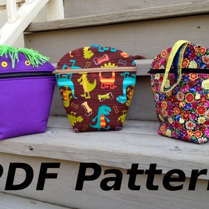 May include: Three different zippered pouches with various fabric patterns. The pouch on the left is purple with a green fuzzy monster face. The middle pouch is brown with a dinosaur and bone pattern. The pouch on the right is black with a floral pattern. The text "PDF Pattern" is at the bottom of the image.