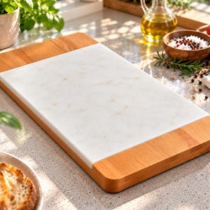 May include: A rectangular serving board featuring a central white marble inlay with subtle grey veining, flanked by two smooth, light-toned wooden ends. The board has a flat surface and rounded edges, combining natural stone and wood materials.