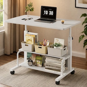 May include: A white mobile standing desk with a rectangular top and a lower storage shelf. The desk features four caster wheels, a laptop displaying 10:30, three storage bins containing books and pens, and a stack of books on the lower shelf.