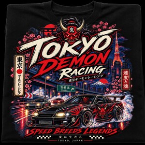May include: A black t-shirt featuring a graphic print of a modified sports car on a city highway at night. The design includes a red oni mask, cherry blossoms, a cityscape with a tower, and the text Tokyo Demon Racing and Speed Breeds Legends.